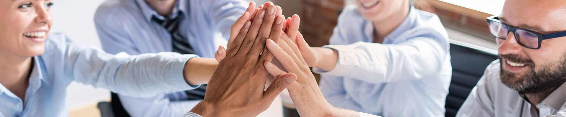 High five of diverse team members in a professional office, symbolizing teamwork and collaboration for Rochester Property Management Group.