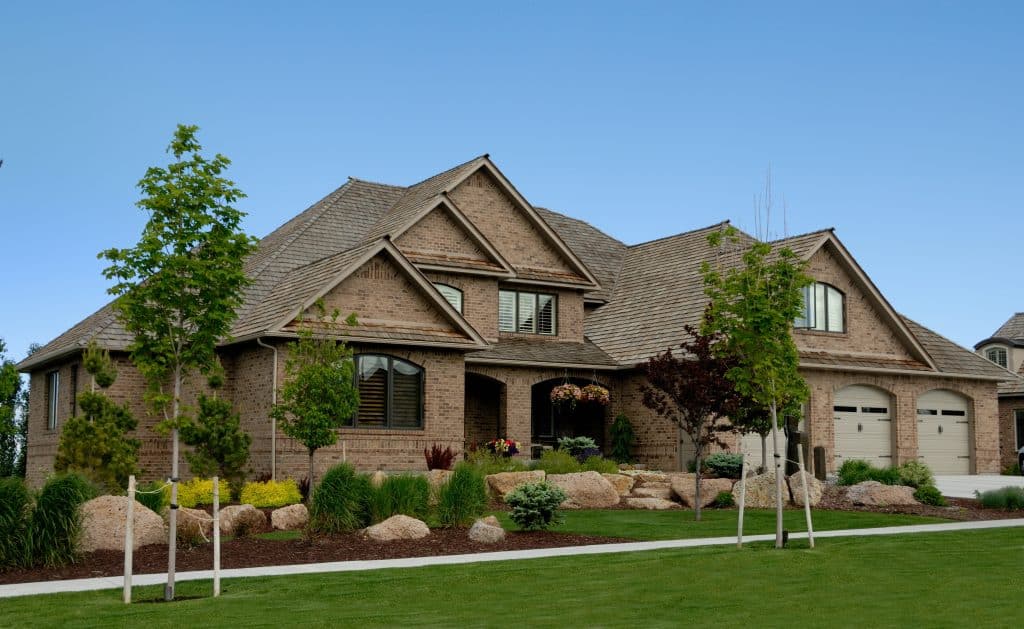 Spacious suburban house with manicured lawn, landscaping, and a brick exterior, showcasing quality property management and real estate services in Rochester.